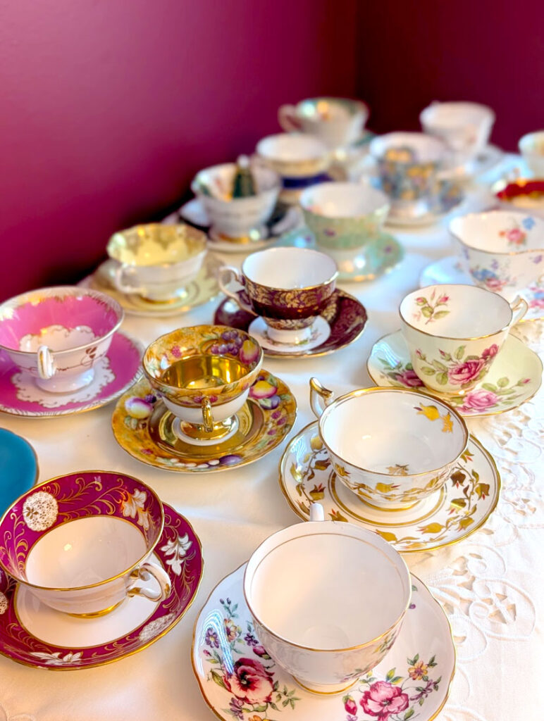 a display of 16 teacups in 3 rows and 6 columns. You can't really see the ones in the back, because they're blurry but you can still tell that not a single teacup is the same. They are all a different pattern, colour, and even shape. 