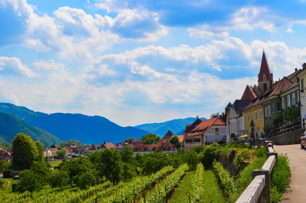 bike Wachau Valley Day Trips Vienna. Wineries below the town, a paved road leads you to the homes of a small town, each building is a different colour, a church steeple rises above the rest. There are more mountains in the distance, they're tinted blue