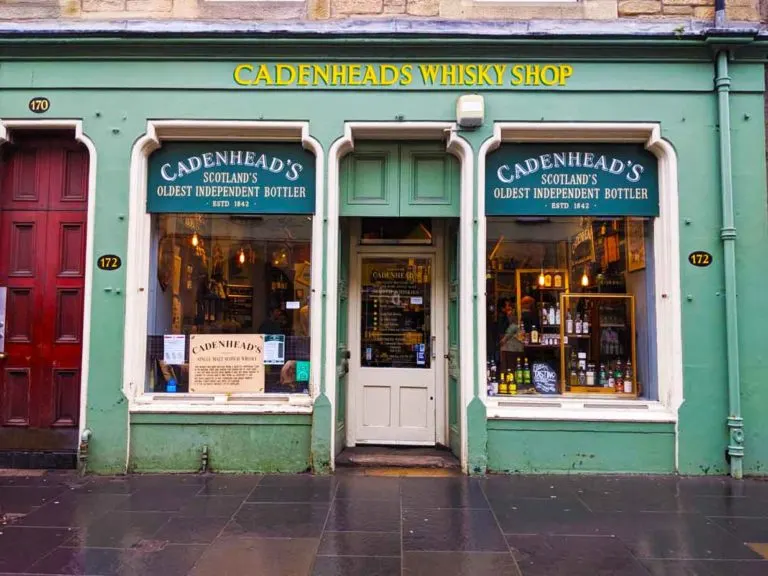 cadenheads-whisky-store-facade in edinburgh: yellow lettering for the shop name on mint green paint. you see some unique whiskey scottish souvenirs in the windows