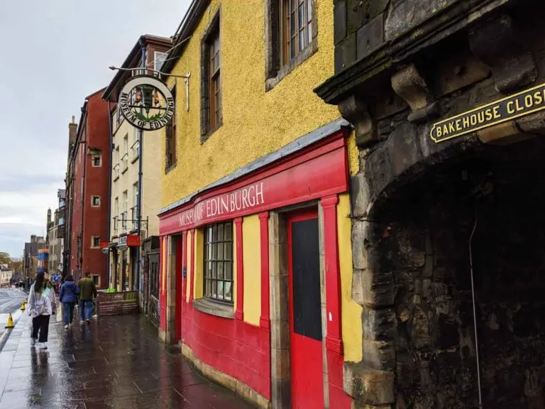 streets of edinburgh on a rainy day seem brighter with a vibrant yellow and red painted building