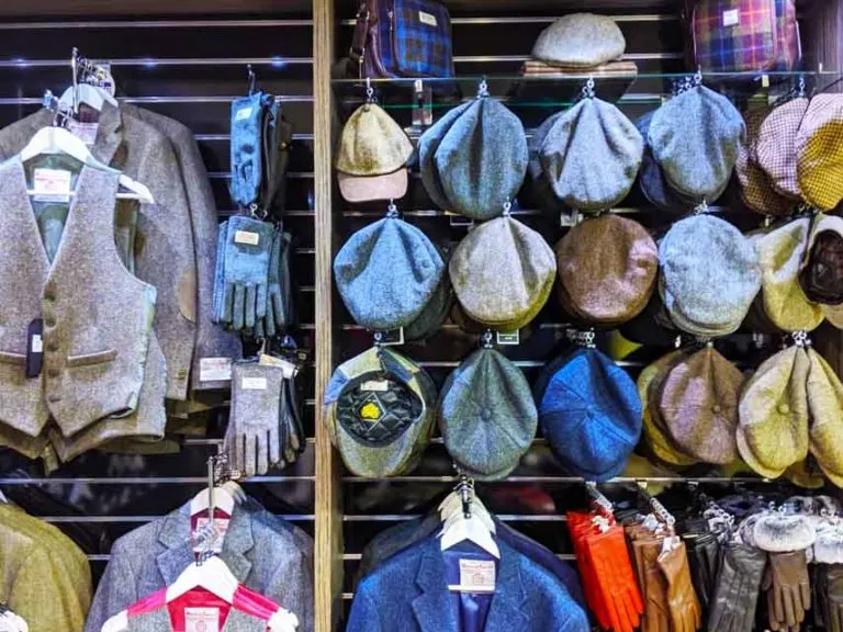 display clothing at Harris tweed in scotland looking for souvenirs: harris tweed vest, gloves, and all styles of tweed hats to choose from hanging on the wall