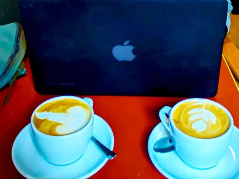 working at a coffee shop in brussels: belga-belga Two cappuccinos and a computer behind