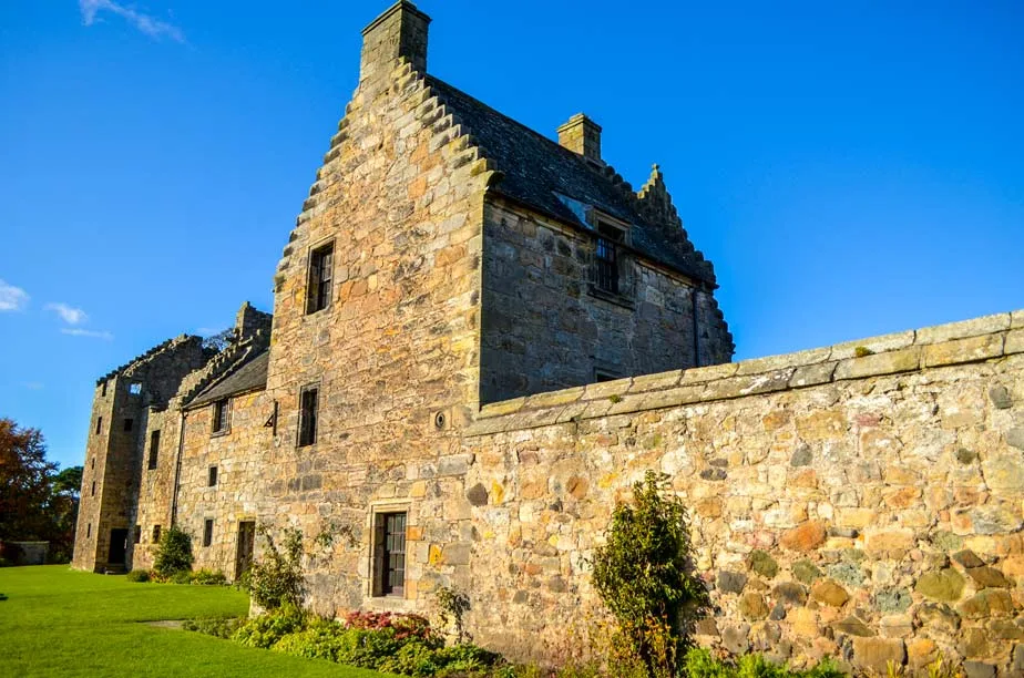 aberdour castle stop from edinburgh to st.andrwes. A long rather than tall stone structure takes up most of the frame, leading from the right all the way to the left. It stones become more ruined and incomplete the further in the distance. 