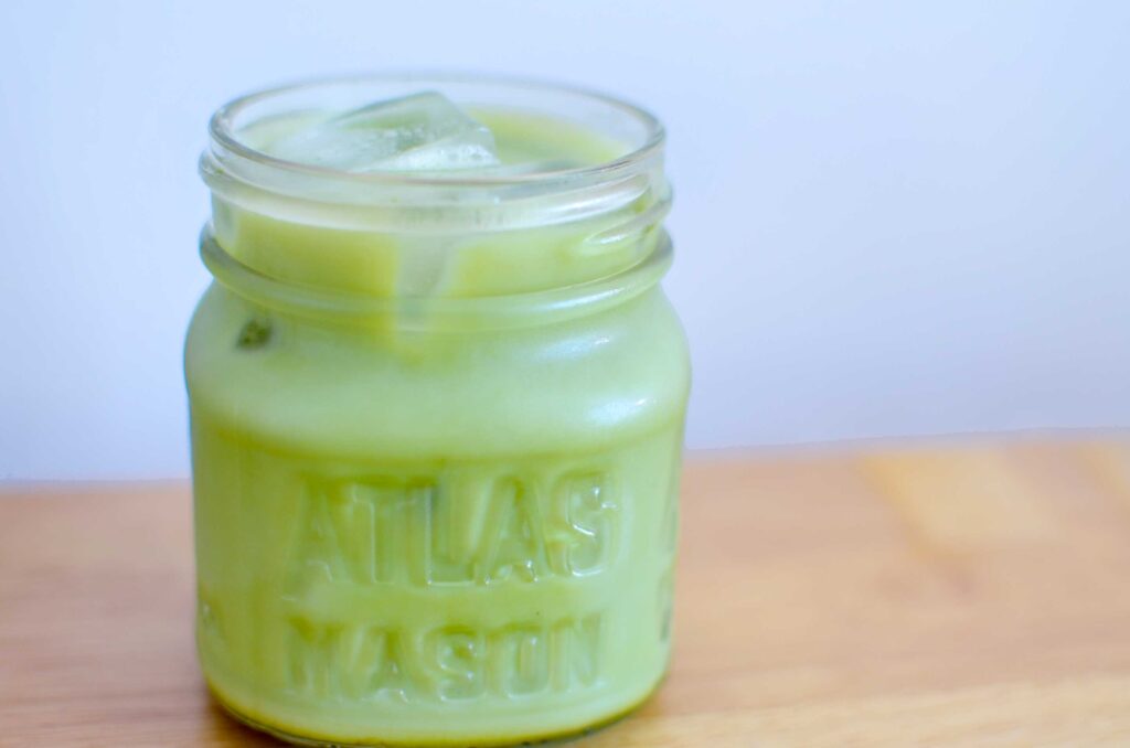 matcha iced cappuccino summer recipes. A mini mason jar filled with a light green and iced drink on a table