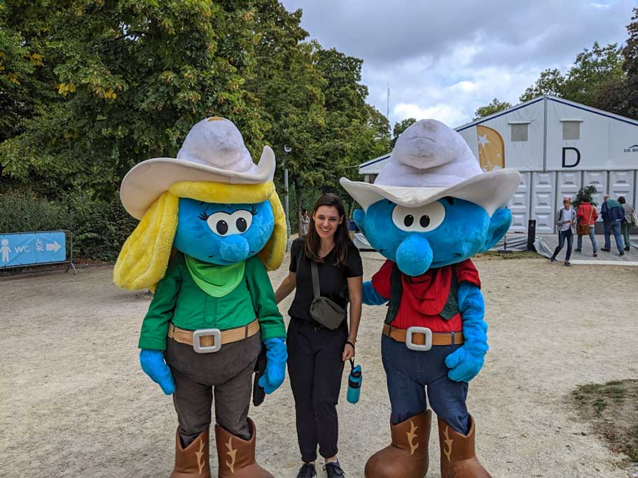 at the brussels comic strip festival, a woman dressed in black, poses wtih two cowboy themed blue smurfs.