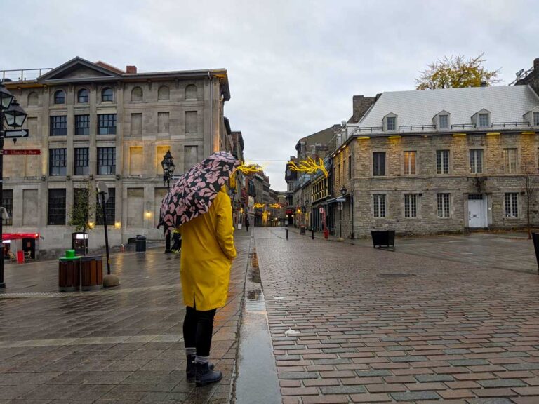 girl standing in yellow rain jacket in Montreal old port while it rains
