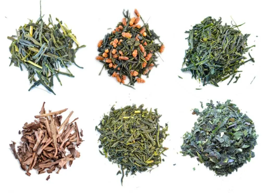 six different types of green teas. The dried leaves are separated into six piles on a white background. From the top left: bancha, genmaicha, sencha, hojicha, gyokuro, and tencha