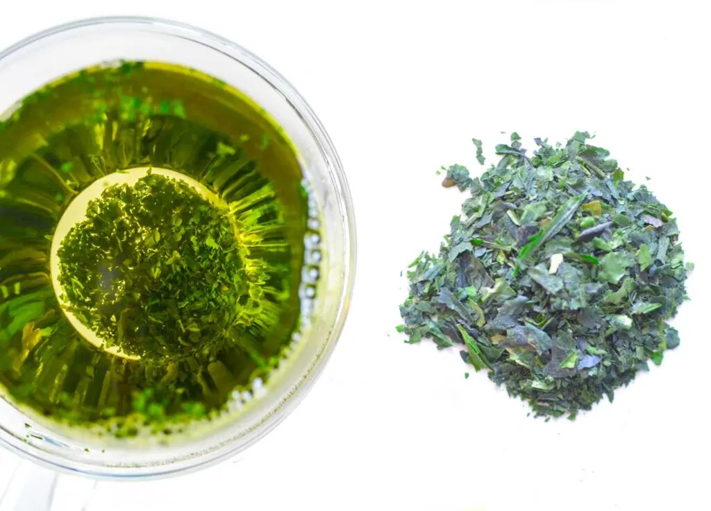 side by side comparison of the dry tencha Japanese tea leaf and the steeped tea in a doubled walled glass mug, and you can see the wet leaves on the bottom.
The left is the steeped tea, which is alost yellow and green vibrant neon color. The pile to the right of it are ripped of bright green peices of the tea leaf.