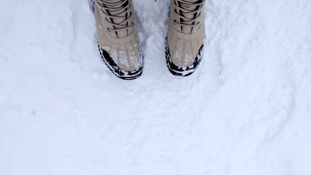 a top down view of the toes of ugg adirondack boots stepping on snow. 