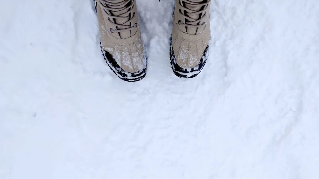 a top down view of the toes of ugg adirondack boots stepping on snow. 