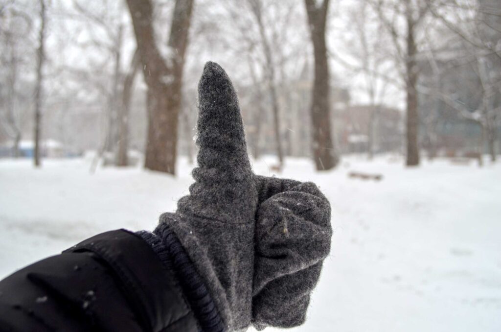 thumbs up with winter gloves on snow in the background