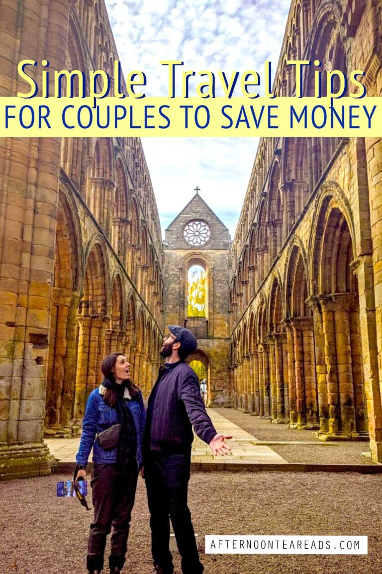 couple staring up at roofless abbey ruins ; simple travel tips for couples to save money