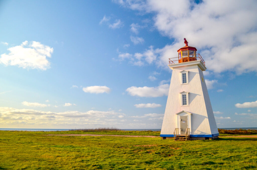 cape edgemont prince edward island canada lighthouse stand tall on completely flat land around it. 

The base is blue, the middle is white, and the top is red. On the ride side, you can see a yellow star. 