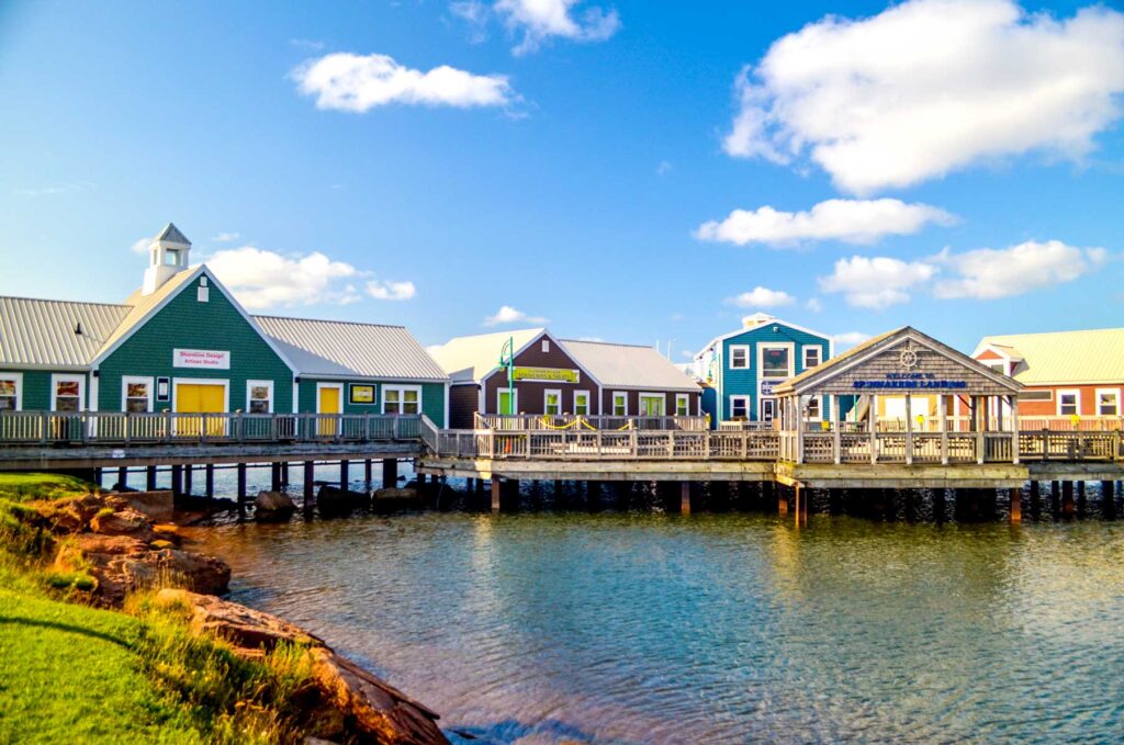 spinmakers landing summerside pei. A set of one story buildings raised on a dock over water. 