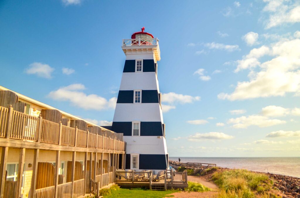 west point lighthouse stands out on Prince Edward Island as it's painted in white and black stripes. The top of the lighthouse is still painted red though. 

Attached the lighthouse is two story long building with balconies facing the water. 