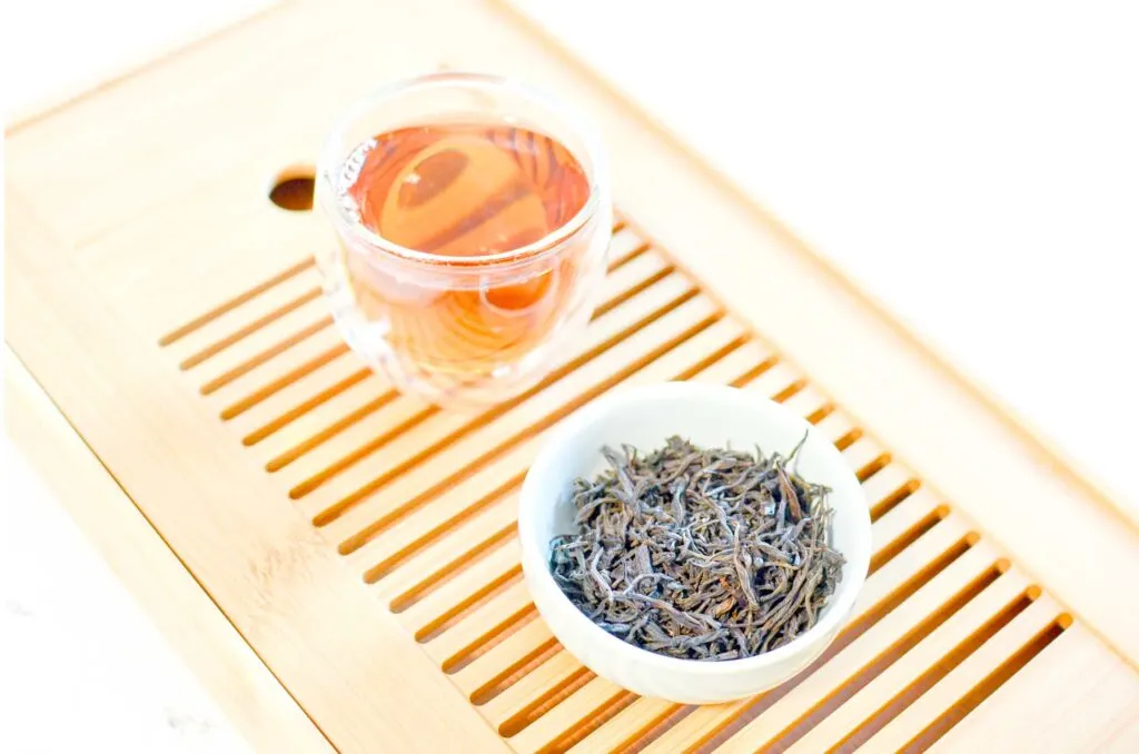 black tea on tea tray with loose leaf leaves and brewed tea