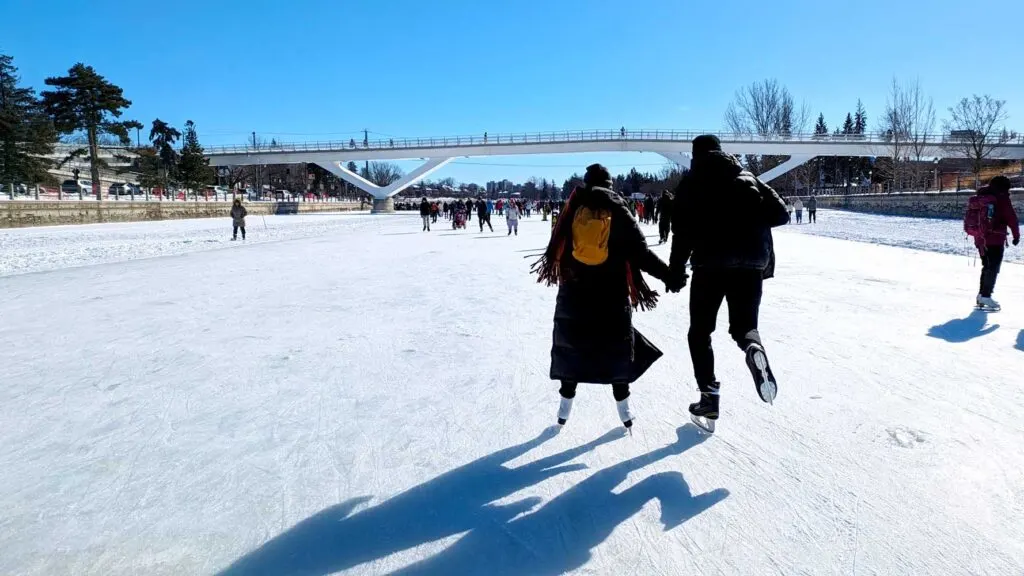 a-couple-from-behind-skating-on-a-sunny-day-on-the-rideau-canal-in-ottawa-in-the-winter