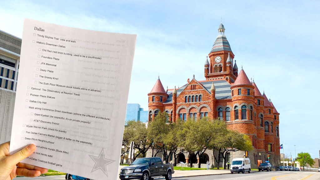 a hand holding up a full 8.5 x 11 paper with a dallas checklist on it. In the background is the old red brick building in dallas