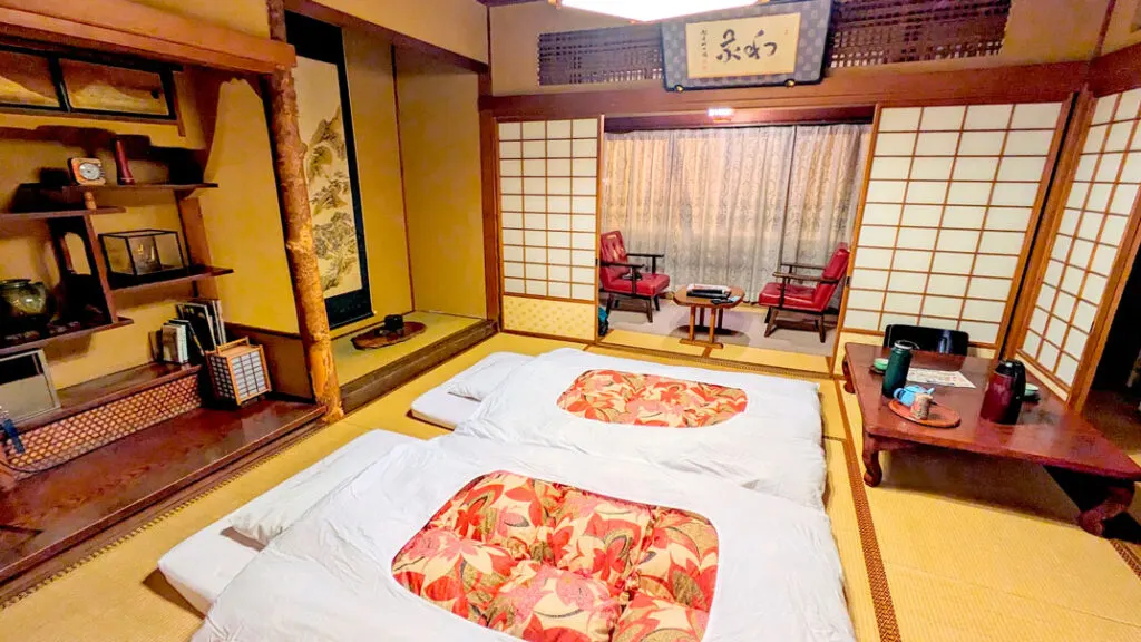 futon beds on the floor at a traditional japan ryokan in shibu onsen at the kanaguya hotel. There are sliding paper doors surrounding the room and wood framings. The floor is a traditional tatami