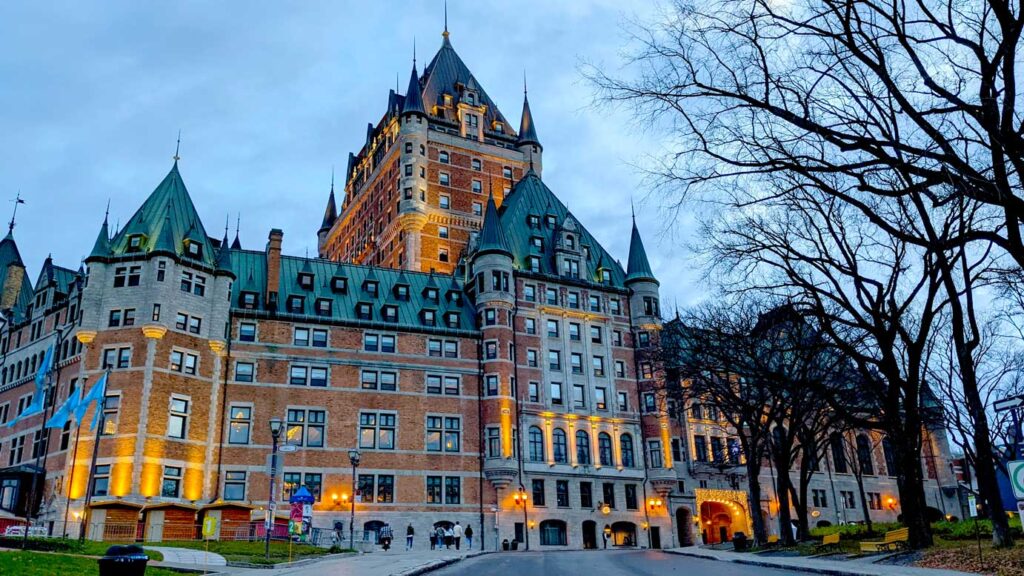 creepy-chateau-frontenac-lit-up-at-dusk-with-a-leafless-tree-in-the-corner-in-the-spring