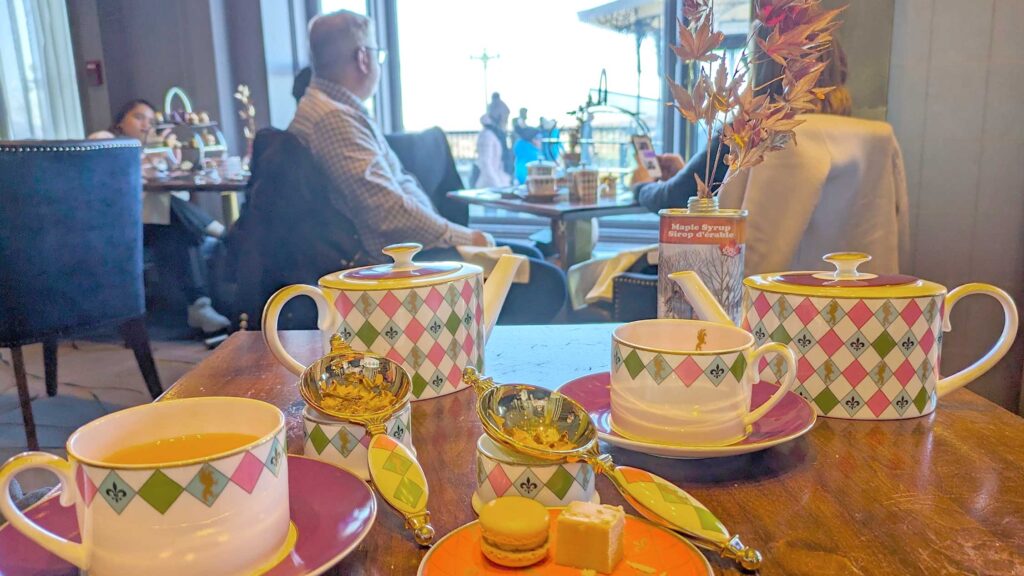 green and pink argyle teapot and matcha cups at place dufferin in quebec city. the table is the second row of seating wtih people in front looking out onto the window