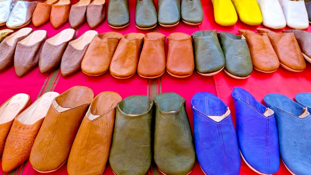 three rows of babouche, traditional moroccan slippers to buy as a souvenir from morocco. Each one varies in size , colour and design. Although ost are brown, there are green and bright blue and yellow options too