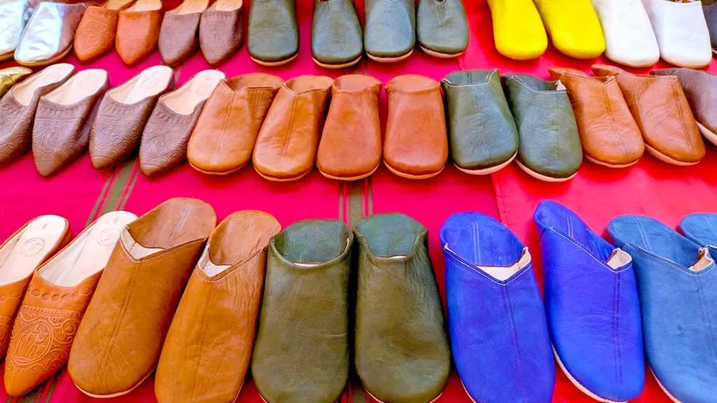 three rows of babouche, traditional moroccan slippers to buy as a souvenir from morocco. Each one varies in size , colour and design. Although ost are brown, there are green and bright blue and yellow options too