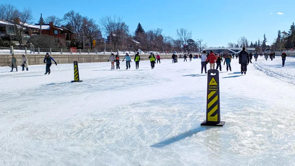 the rideau canal skate way view of it trailing all the way into the distance. But in the front is a yellow and black diagonal striped pillar in the middl of the ice. 

It says caution, and you can see the difference in the ice conditions. It's already melted underneath the sign. There's a pool of water and slush surrounding it. 

Across the ice to the left, is another of the same sign. 

But there are a few hundred people still skating on the ice, just around them. 