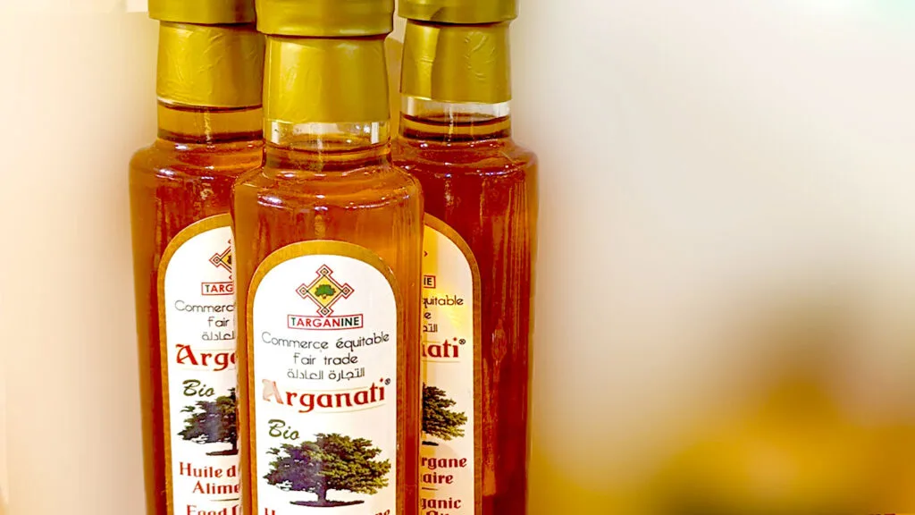 a close up photo of three tall bottles that say on the label: fair trade Arganati, Huile d'argane Alimentaie (translates from french to culinary argan oil). 