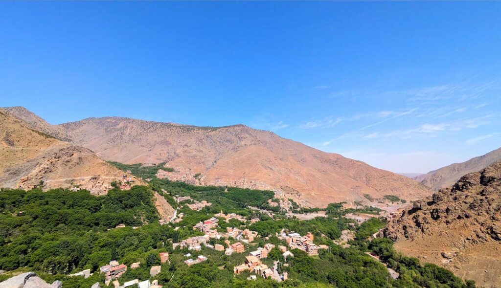 Three yellow rocky mountains surround a valley with trees and villages in the middle. But you can also make out some village built into the rocky moutnainside, they blend in so well that they're hard to see.