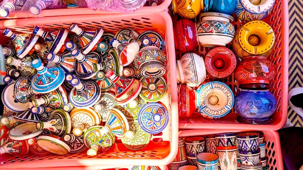 2 levels of pink plastic open crates are photographed from above. Inside the top one are a lot of mini ceramic painted tagines - the perfect moroccan souvenir for friends and family