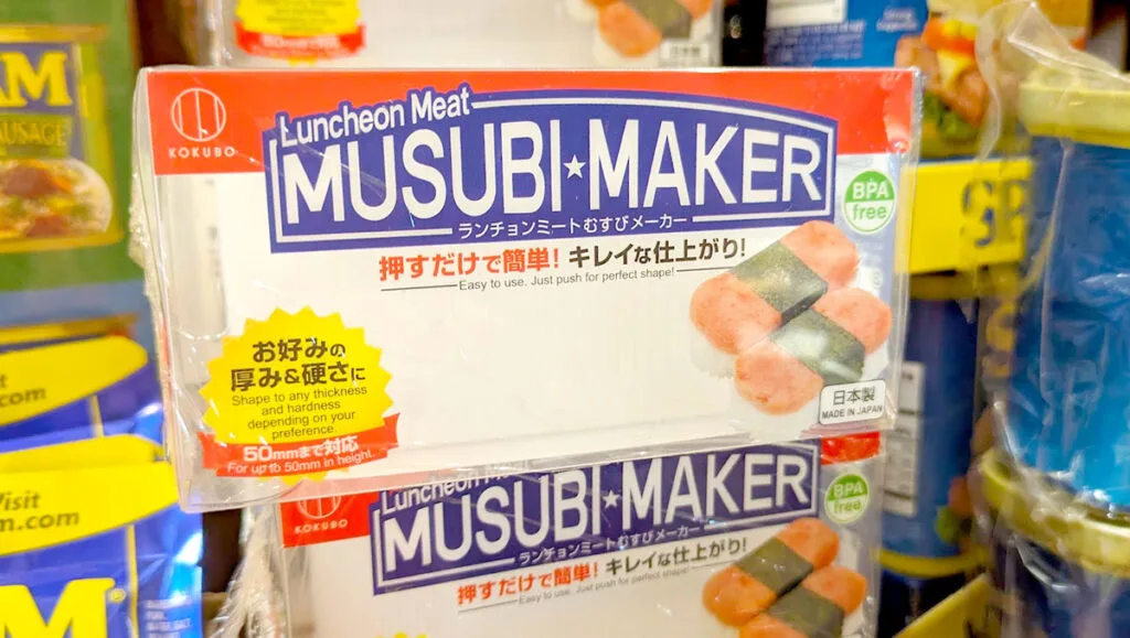 a closeup of the packaging for the musubi maker. There's japanese writing on the box as well, in english it says: easy to use. Just push for perfect shape! There's an image of SPAM musubi in the corner. 