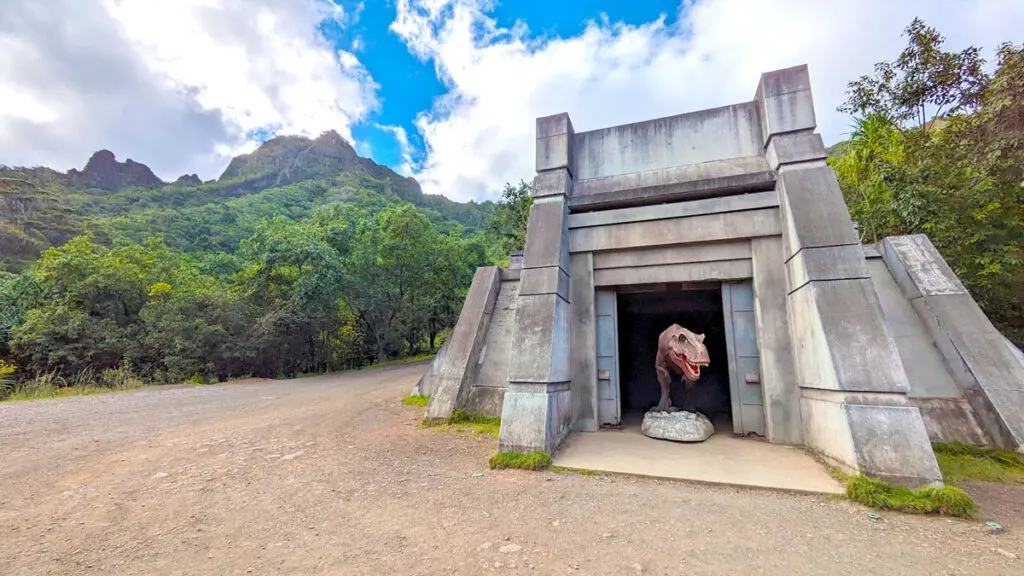 a set from jurassic world is still at the kualoa ranch. It's stone building with a t rex sticking his head out of a black hole. There's a dirt road around it and mountains and blue skies in the distance. 