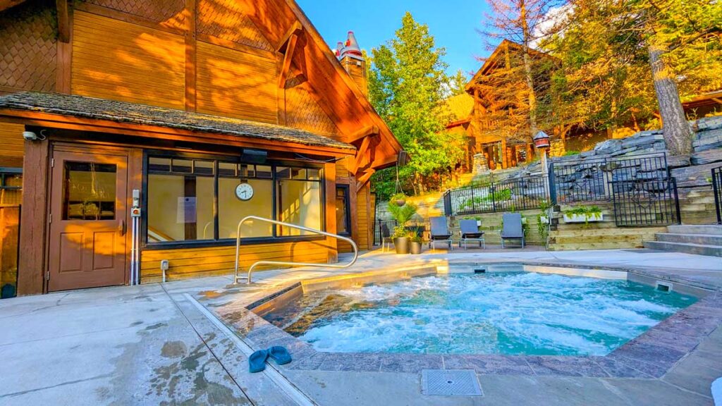 the glorious in ground hot tub at the buffalo mountain lodge at sunset. It's a stone pathway around the bubbling hot tub as the jets are on. The sun is hitting the surrounding lodge above it, adding a beautiful warmth to the image. 