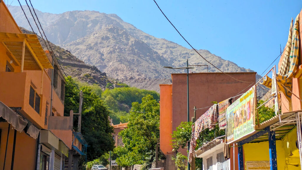 Imlil high atlas mountains, the largest town with ads and blankets hanging out to try over the rooftop edges. The large mountain looms above the buildings in the distance.