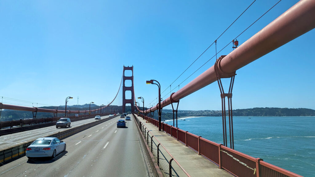 four lanes on the road, two in each direction are suspended by large red suspensions that go into a red tower as you drive across the bay on the golden gate bridge.