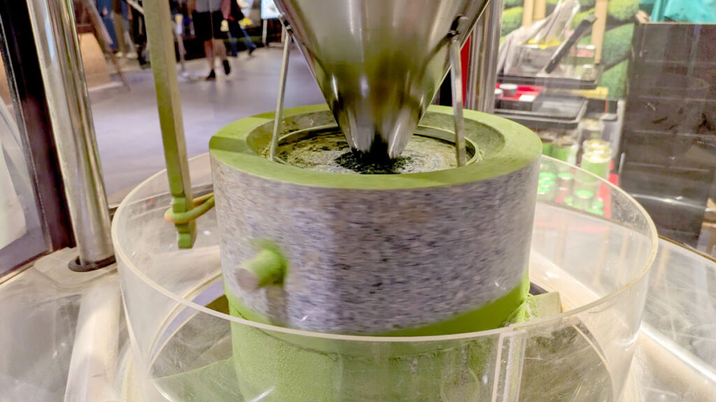 a large cylinder in the centre that has green powder on the top and bottom of it. It is turning tea leaves into matcha powder, it's like a giant motorized mortar and pestle.