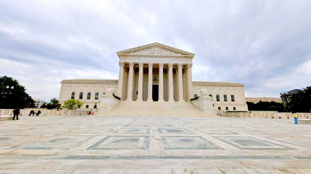 the supreme court of the united states is beautiful but barren. The floor is a gorgeous hard marble pattern, but there's not an ounce of shade, and no one is walking on it. It must be stifling to walk out there.  It's a far way to get to the building in the back, with a centre and it's barred off with pillars to hold the triangular roof. 